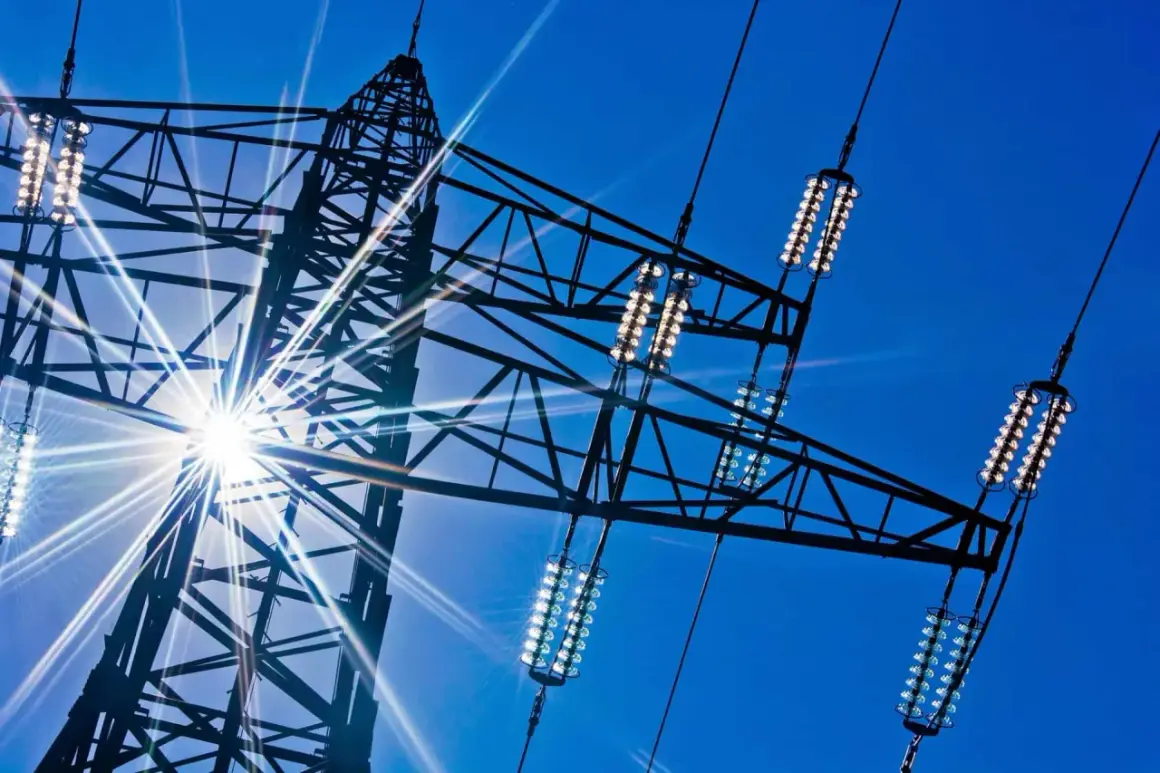 Słońce przebija się przez kratownicę wieży energetycznej, oświetlając izolatory przewodów, które przenoszą prąd dwufazowy.