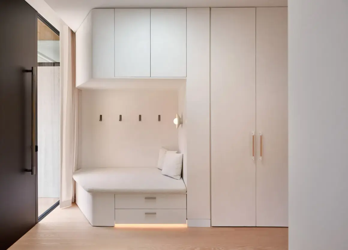 Banquette intégrée avec rangements sous pente, murs clairs, parquet bois.