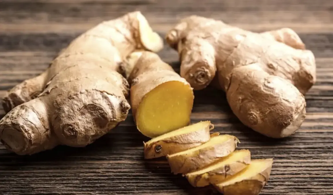 Raíces de jengibre enteras y cortadas en rodajas, mostrando su interior amarillo vibrante. Un tesoro natural con innumerables propiedades del jengibre.