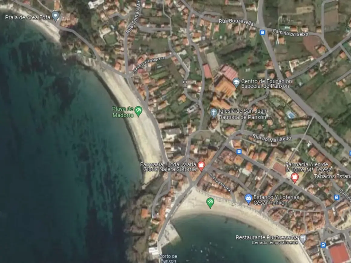 Vista aérea de la **playa de Madorra**, con el mar turquesa y la arena dorada. Se aprecian edificios y calles cercanas.