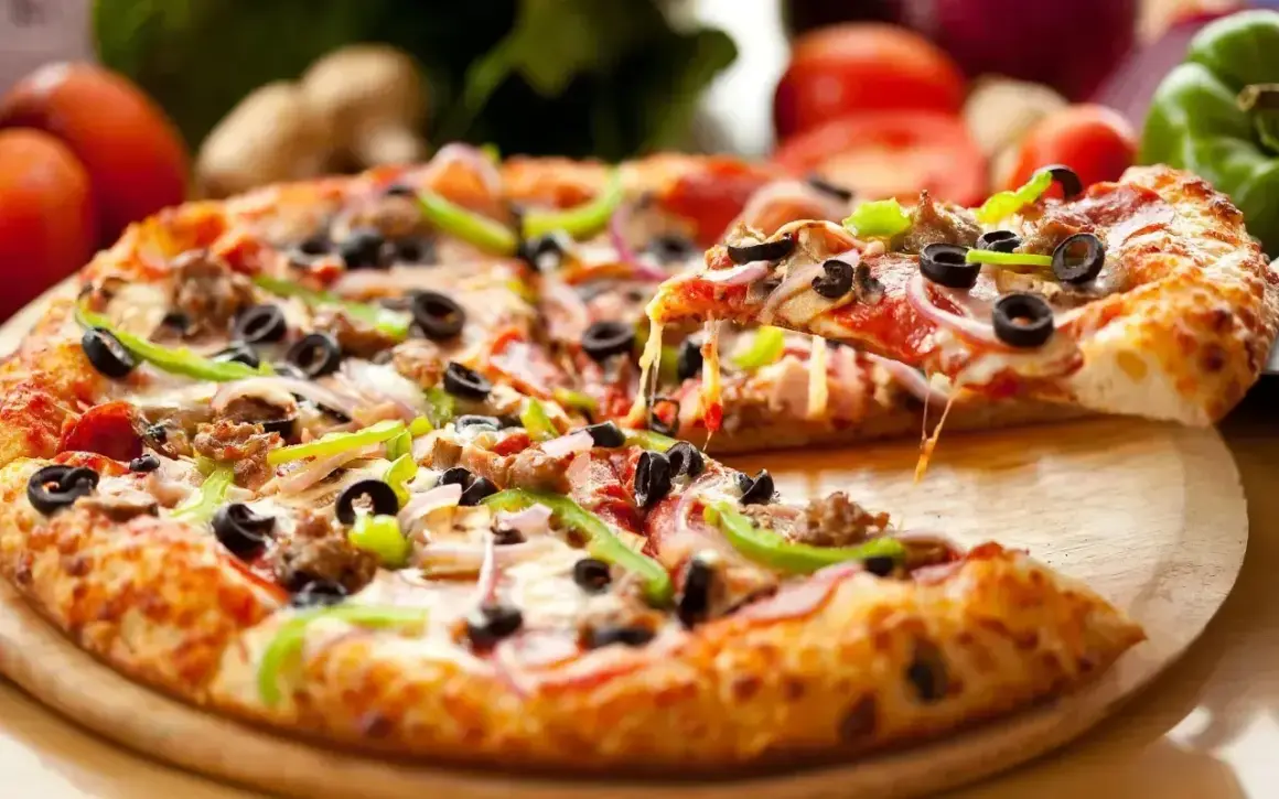 Idealna pizza na światowy dzień pizzy: gorąca, ciągnący ser, oliwki, papryka i mięso.