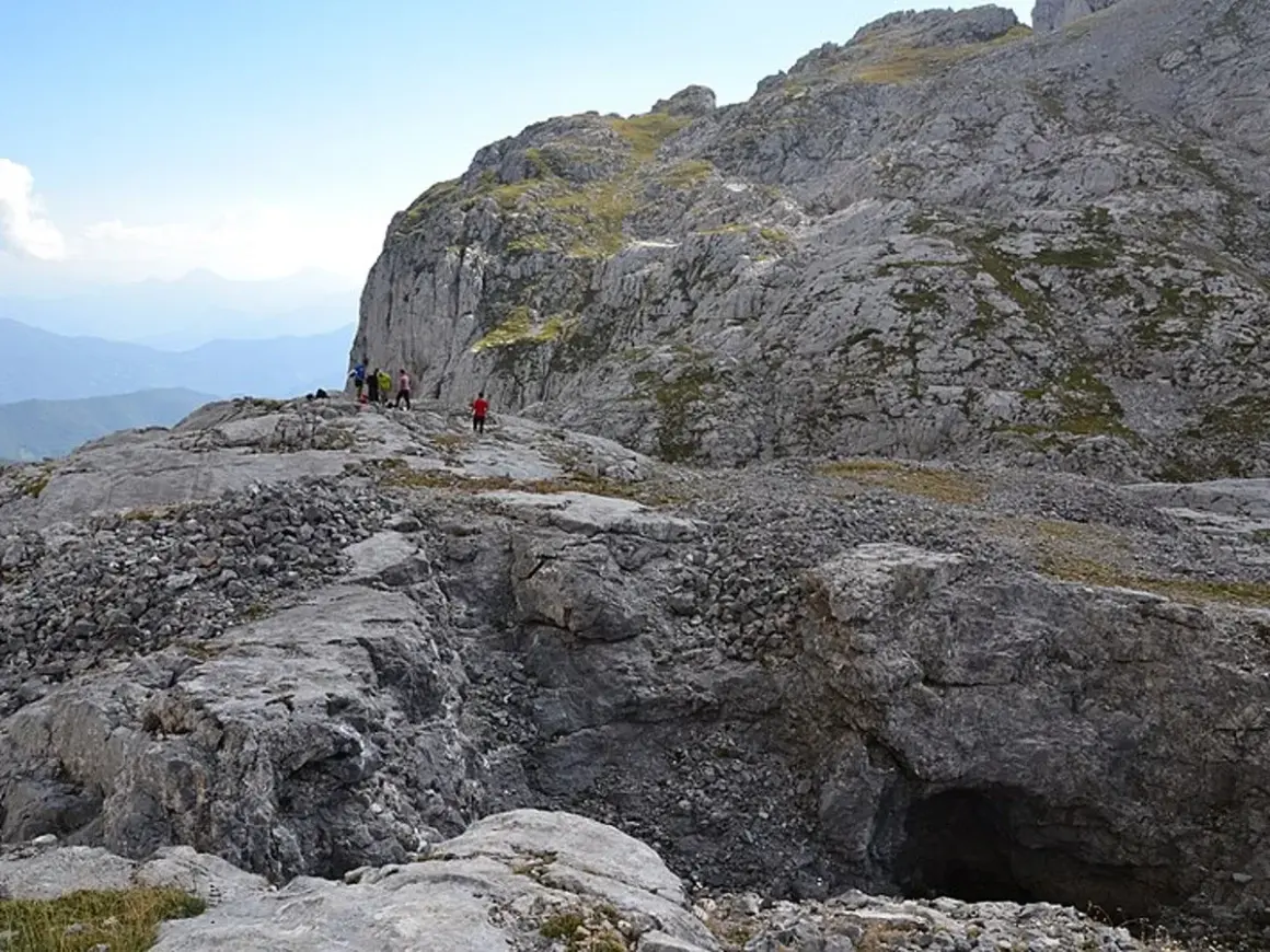 Senderismo en la vega de Liordes, un paisaje rocoso con un grupo de personas observando un abismo.