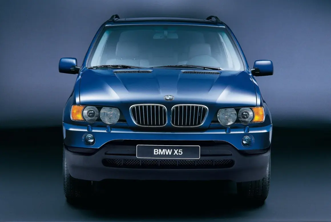 Niebieski BMW X5, pierwszy SUV tej marki, znany z wiki. Klasyczna krata i okrągłe reflektory.
