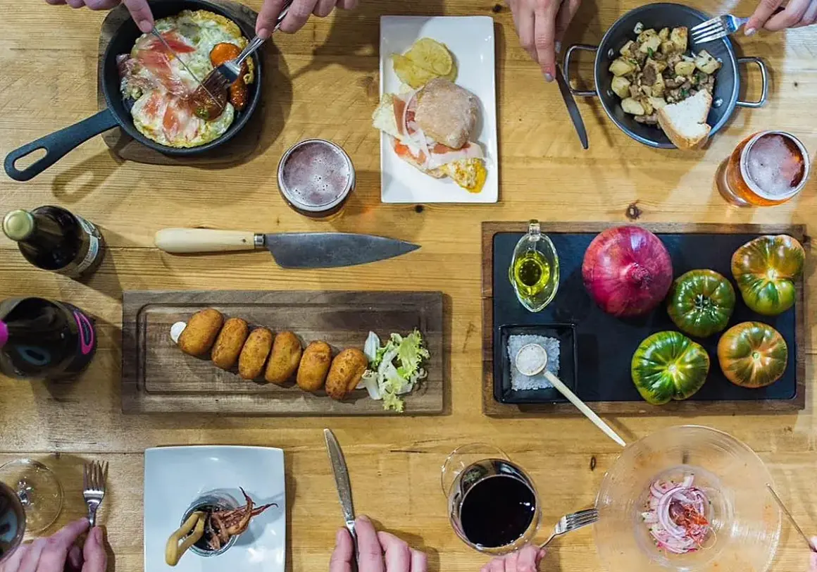 Una mesa llena de delicias para una ruta tapas: croquetas, montadito, huevo con jamón, patatas y calamares. ¡Buen provecho!