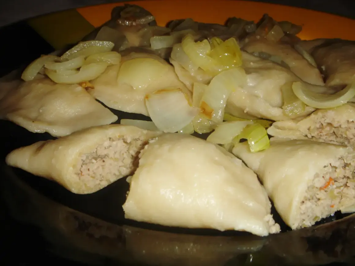 Pyszne pierogi z mięsem i kapustą, polane podsmażoną cebulką, kuszą swoim domowym wyglądem.