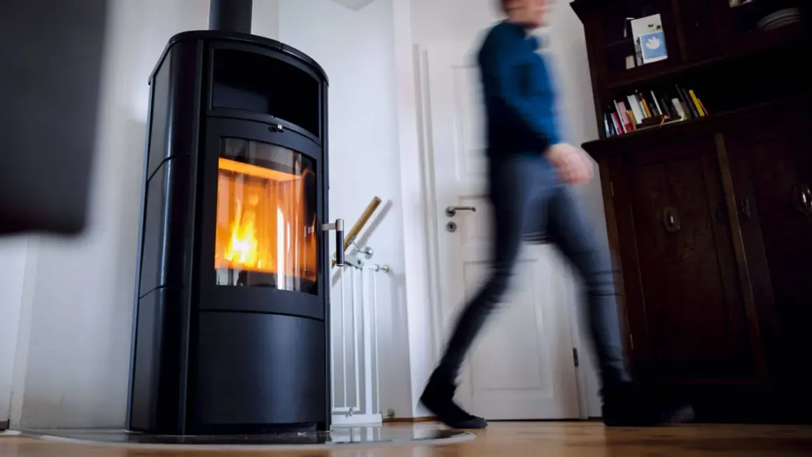 Ein Mann eilt an einer brennenden Holzheizung vorbei. Angesichts des möglichen Holzheizung Verbots 2030, wird diese Heizform bald Geschichte sein.
