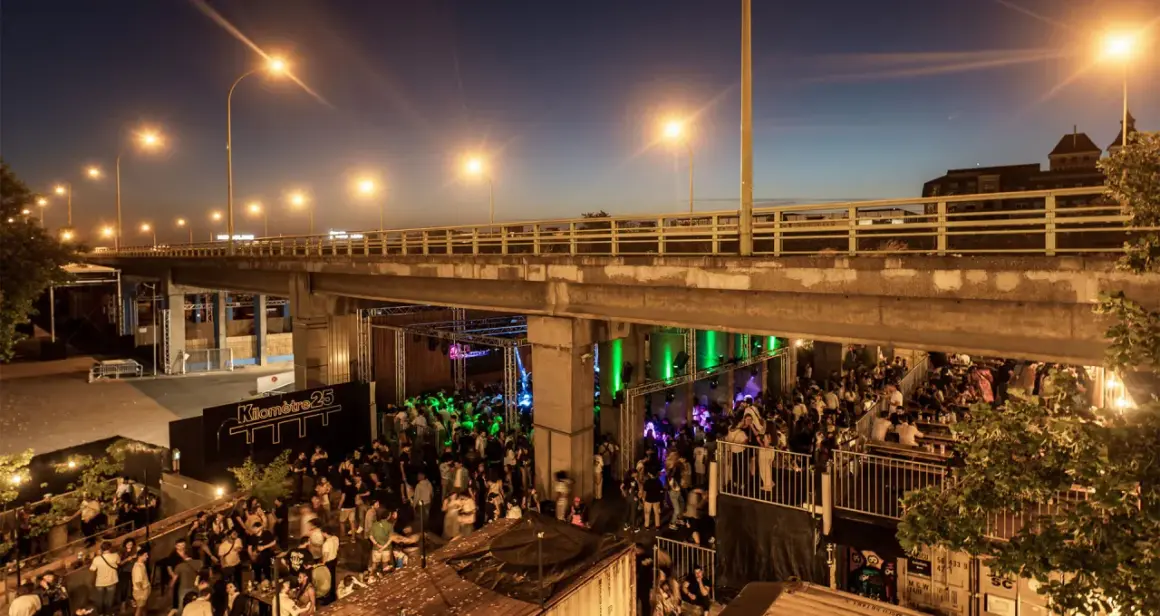 Soirée animée sous un pont, avec une foule dansant et profitant de la musique au Kilomètre 25.