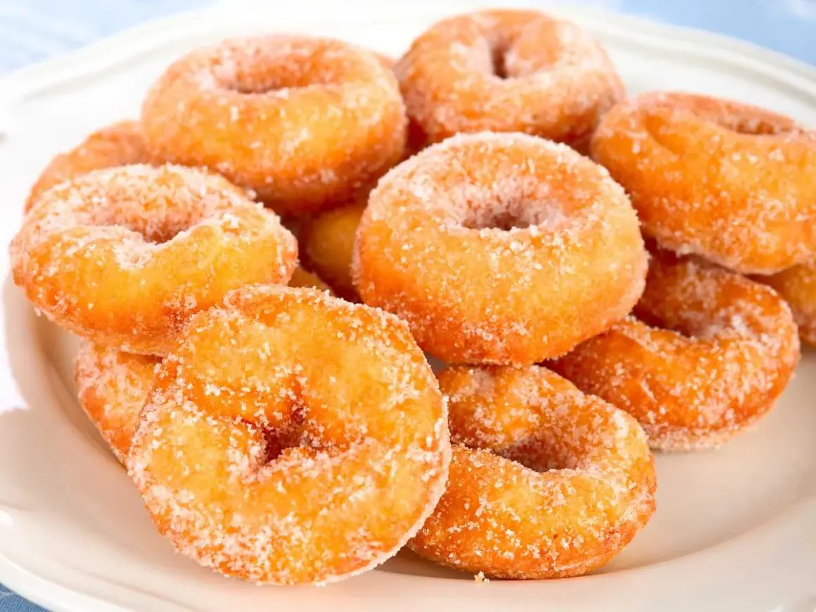 Montón de rosquillas caseras de toda la vida, doradas y espolvoreadas con azúcar.