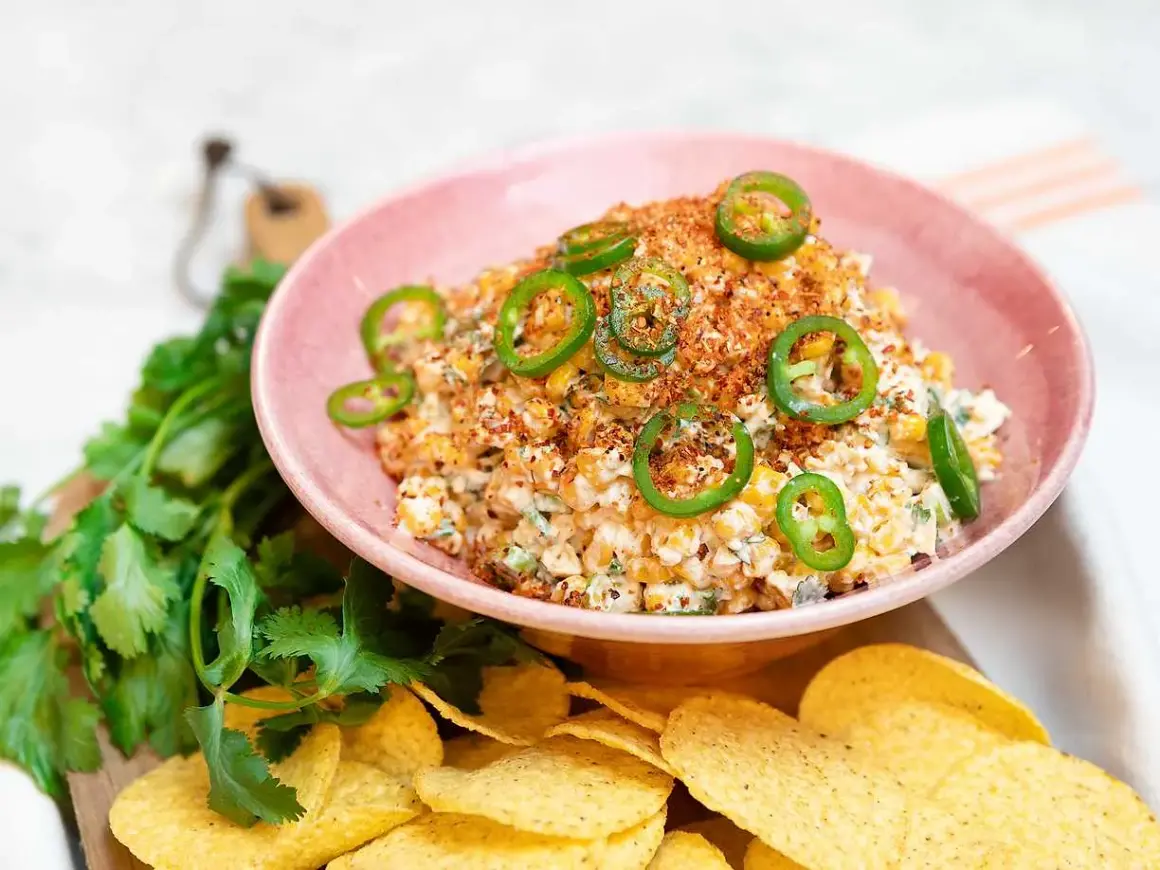 En krämig mexikansk majssallad toppad med jalapeños och serverad med tortillachips och färsk koriander.
