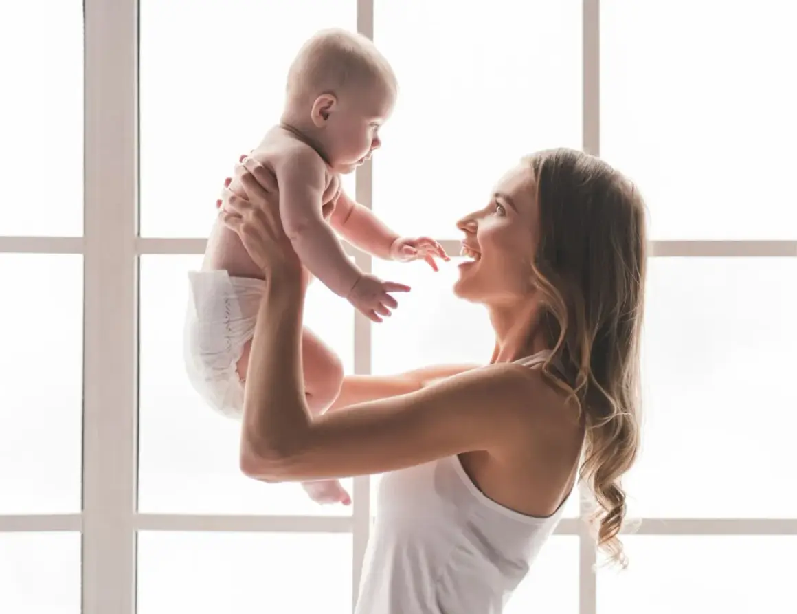 Szczęśliwa mama podrzuca w górę swoje 7 miesięczne dziecko.