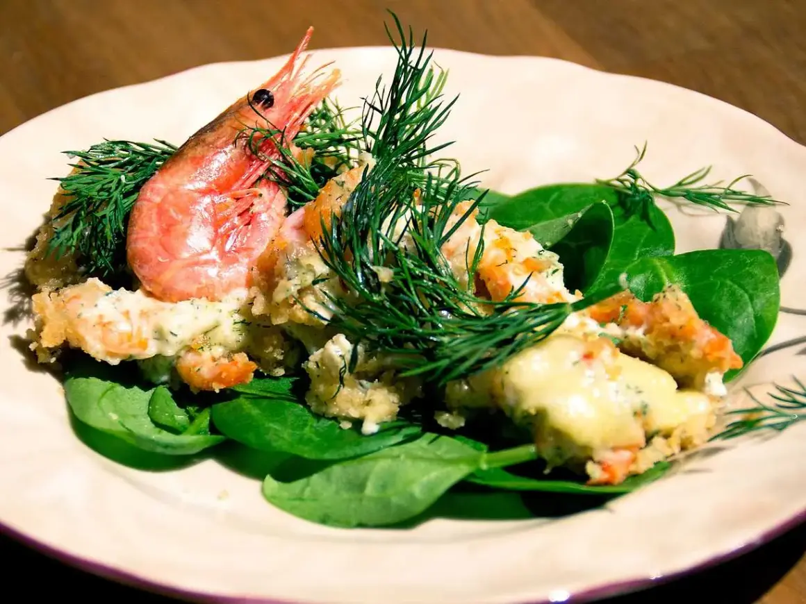 En krämig räkröra med dill, serverad på färsk spenat. Perfekt som sallad till pajen.