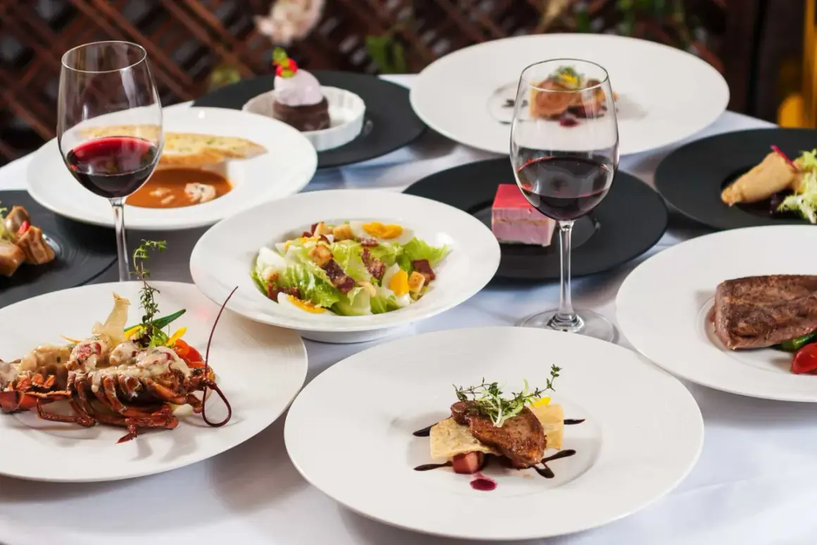 Elegancka kolacja w stylu kuchnia francuska: homar, stek, sałatka Cezar, desery i czerwone wino.