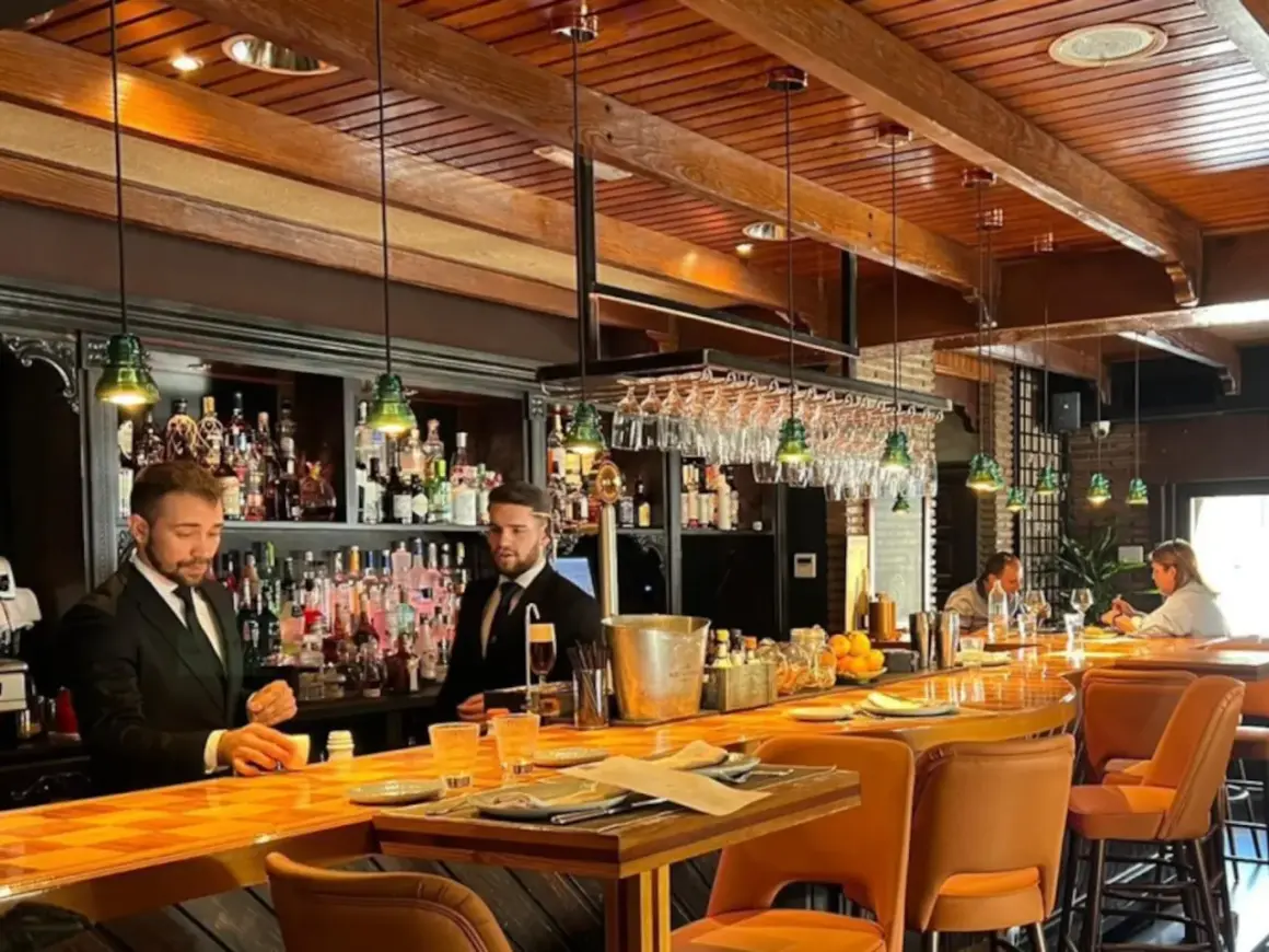 Banqueros sirviendo en uno de los restaurantes el ejido, con un ambiente acogedor y una barra de madera pulida.