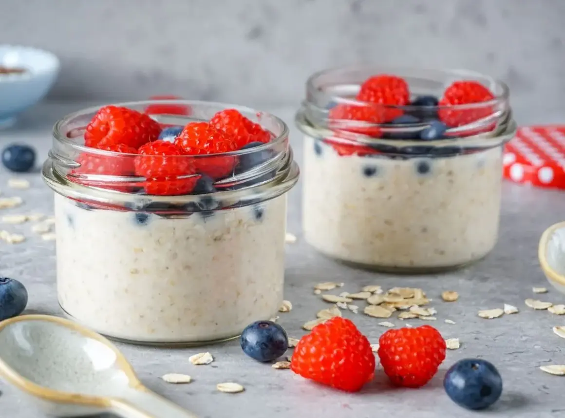 Zwei Gläser mit Overnight Oats, garniert mit Himbeeren und Blaubeeren. Perfekt für gesunde Overnight Oats Rezepte.