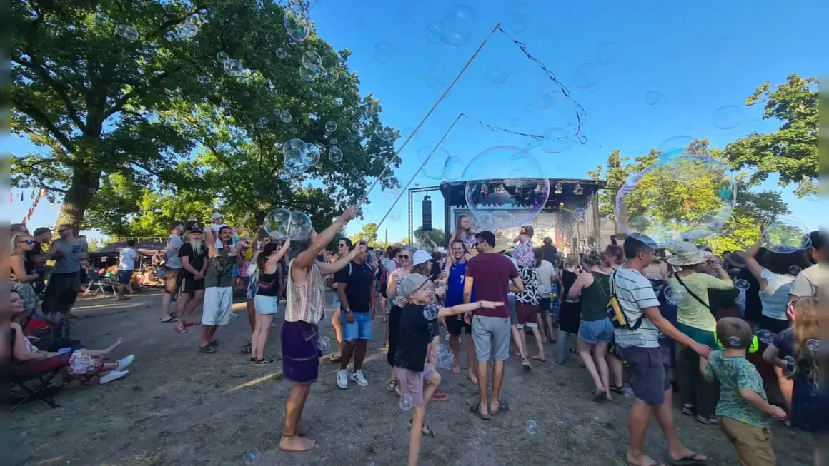 Seifenblasen schweben über einer fröhlichen Menge beim weinturm open air. Kinder und Erwachsene genießen die sommerliche Atmosphäre vor der Bühne.