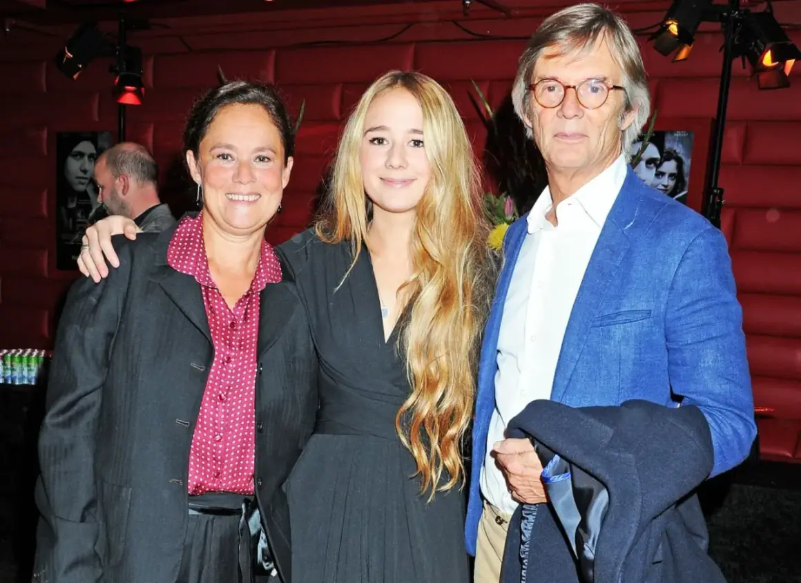 Bille Augusts barn, en kvinna och en ung flicka, poserar med en man i blå kavaj.
