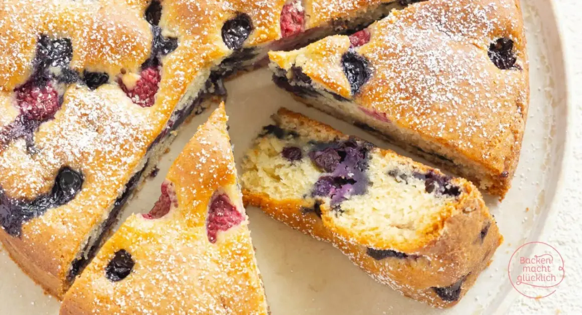 Saftiger, veganer Kuchen mit Blaubeeren und Himbeeren, bestäubt mit Puderzucker. Ein Genuss für alle!