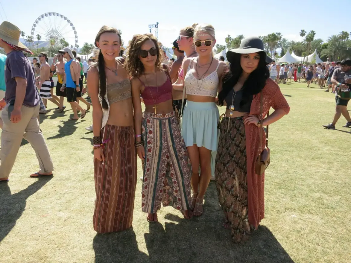 Cztery młode kobiety w letnich strojach pozują na tle festiwalu Coachella.