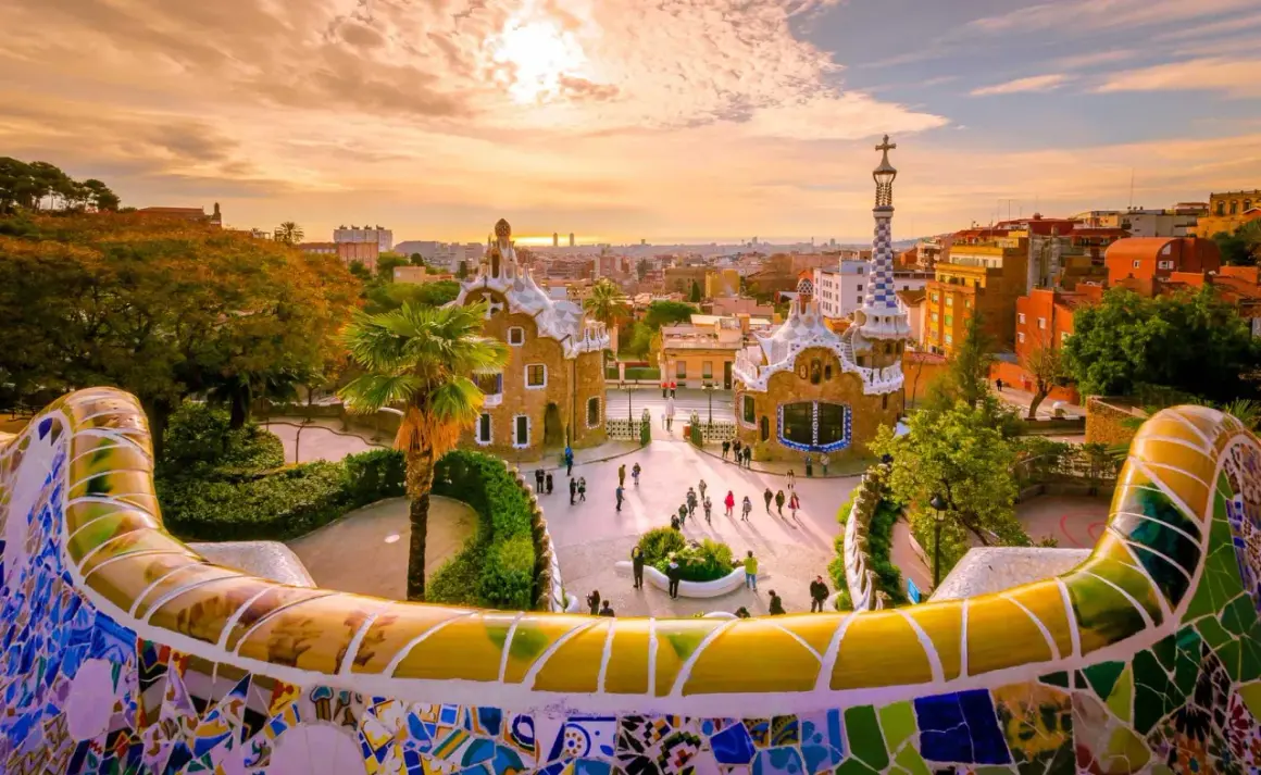 Park Güell w Barcelonie, jednym z największych miast Hiszpanii, zachwyca mozaikową ławką i bajkowymi budynkami o zachodzie słońca.