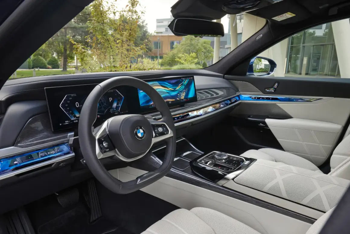 Wnętrze BMW 740d z nowoczesnym panelem cyfrowym, podświetlanymi detalami i komfortowymi, białymi fotelami.
