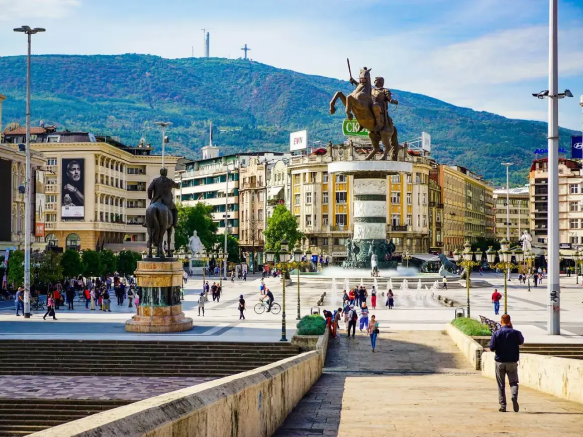 Pomnik wojownika na koniu na placu w Skopje, Macedonia Północna, z górami w tle.