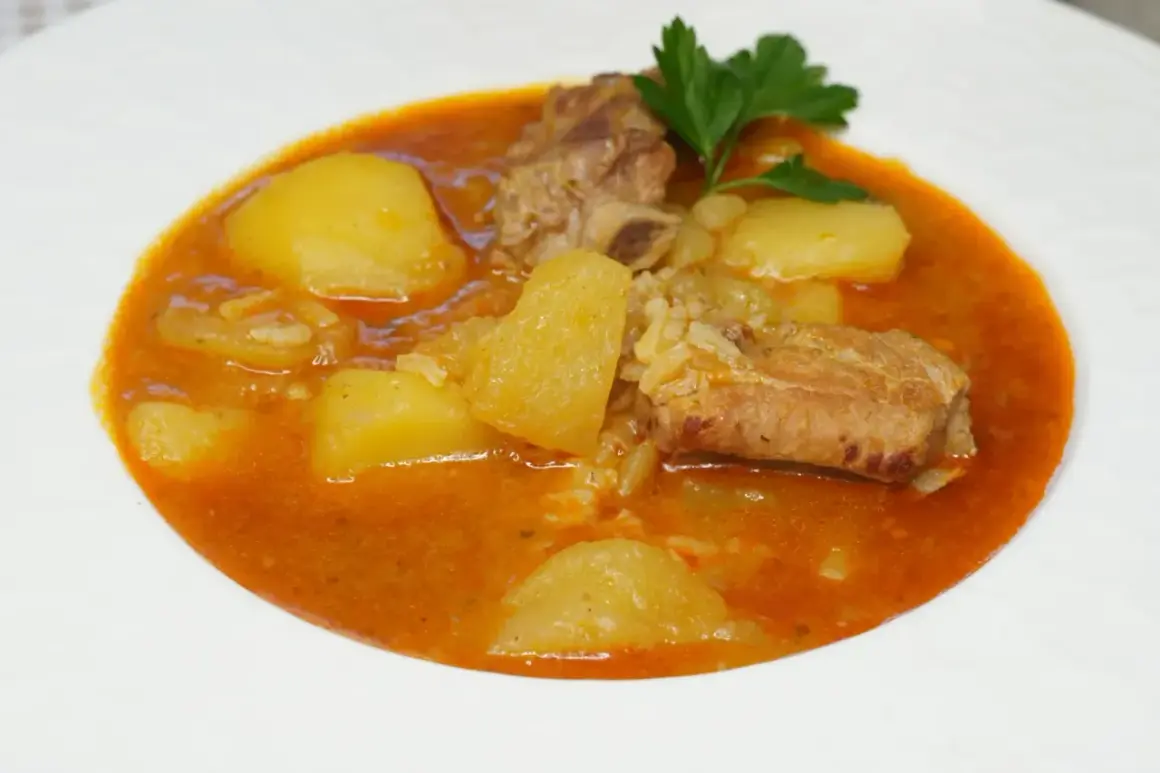 Costillas guisadas con patatas, un plato reconfortante con trozos de carne tierna y patatas en una salsa rojiza, adornado con perejil fresco.