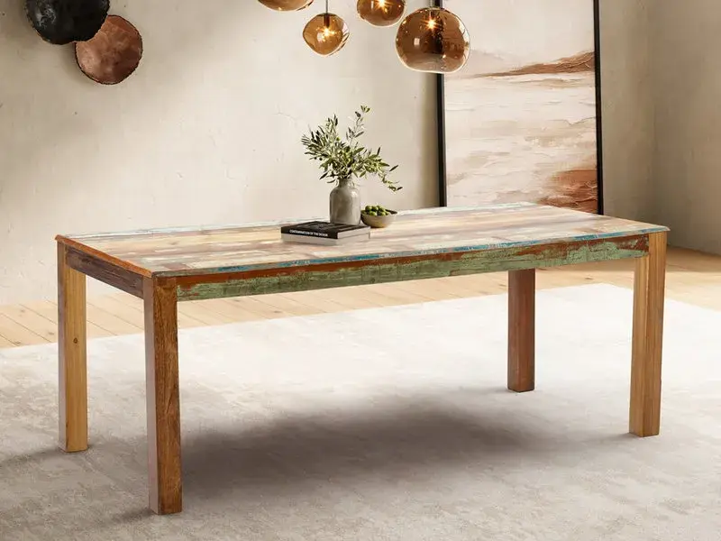 Ein rustikaler Esstisch aus verschiedenen Holzarten mit farbigen Akzenten, der in einem stilvollen Esszimmer steht.