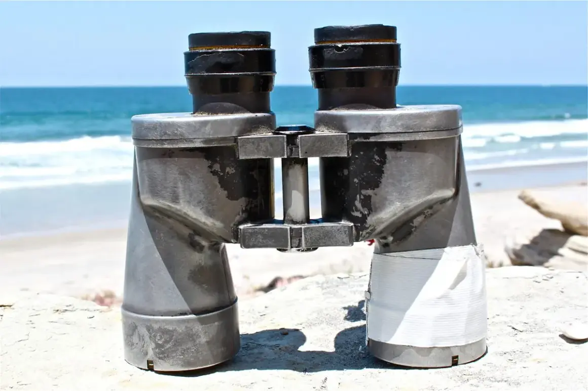 Binocolo sulla spiaggia, pronto a scrutare l'orizzonte. A cosa serve il binocolo? A vedere lontano, a scoprire dettagli nascosti nel paesaggio marino.