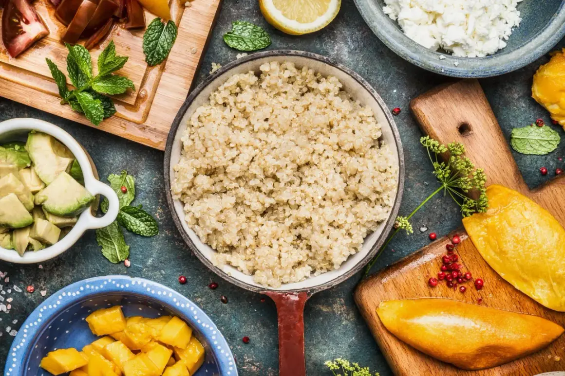Perfekt gekochtes Quinoa in einer Pfanne, umgeben von frischen Zutaten wie Avocado, Mango und Tomaten.