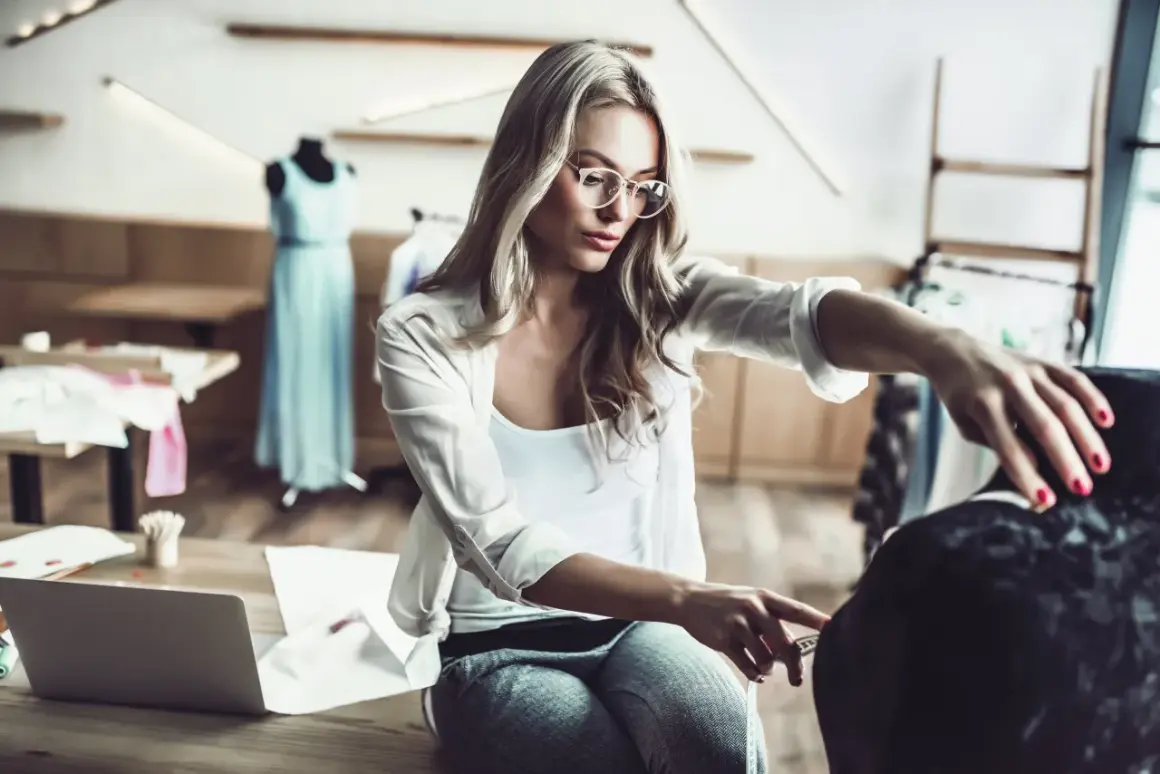 Eine Designerin mit Brille misst Stoff für ihr nächstes Projekt im Bereich IU Modemanagement.