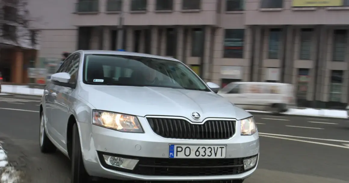 Srebrna Skoda Octavia 1.6 TDI jedzie ulicą miasta.