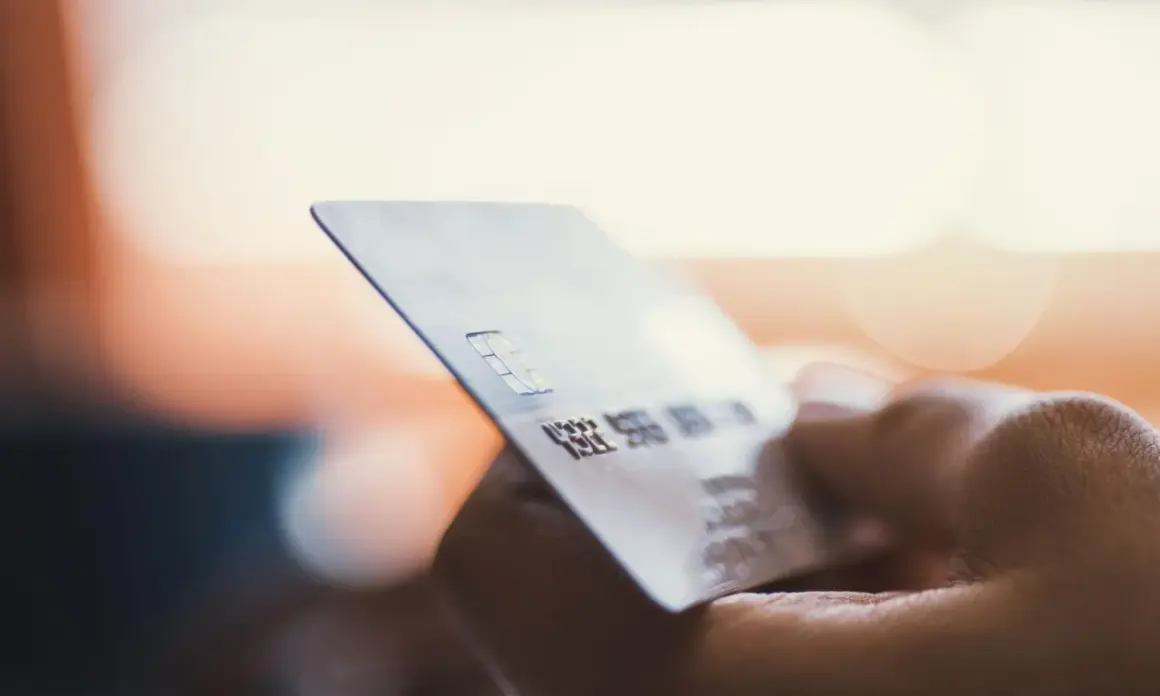 Dłoń trzyma kartę płatniczą. Zastanawiasz się, moneyback co to? To zwrot części pieniędzy za zakupy.