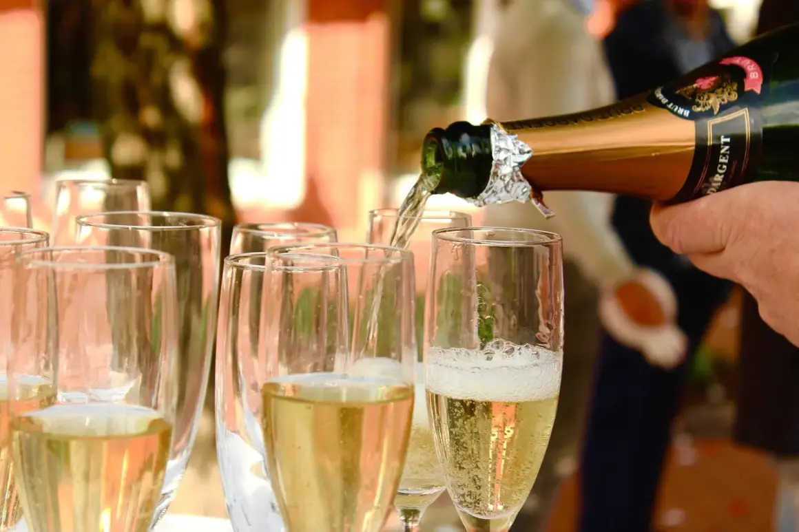 Nalewanie złotego **brut wino** do kieliszków. Bąbelki unoszą się, zapowiadając celebrację.