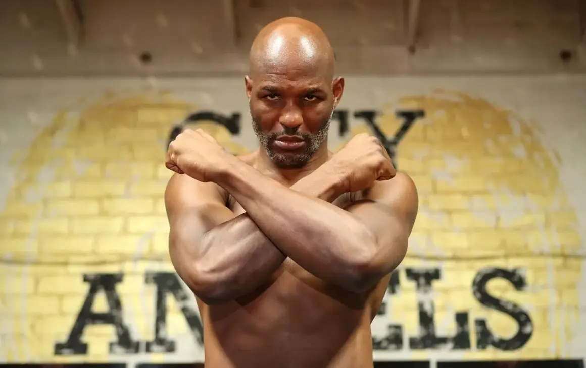 Bernard Hopkins, the legendary boxer, stands with arms crossed, a determined look on his face. He's a true inspiration, a master of his craft, and a great trainer.