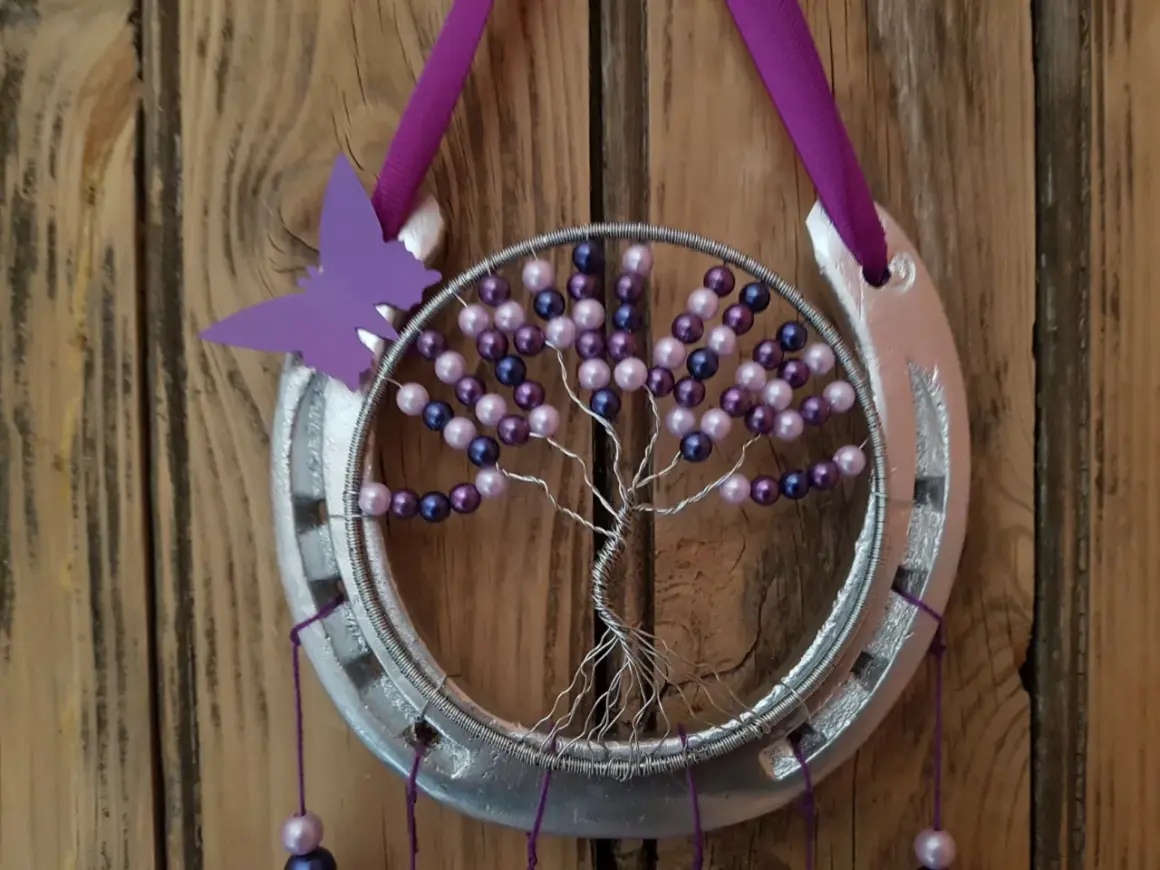 Tuto attrape rêve arbre de vie : un fer à cheval argenté orné d'un arbre de vie en fil de fer et perles violettes et roses, avec un papillon violet.