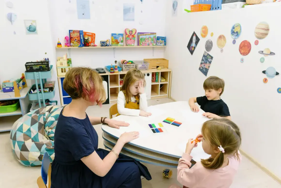 Ergotherapie Teilzeit Ausbildung: Kinder malen und basteln mit einer Therapeutin in einem bunten Raum.