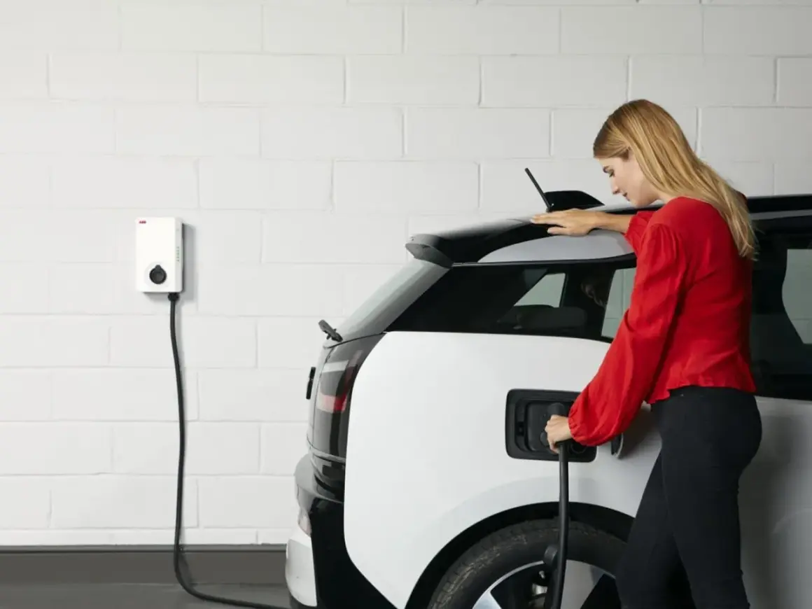 Femme branchant sa voiture électrique sur une borne. Une solution pratique pour le crédit d'impôt borne électrique.