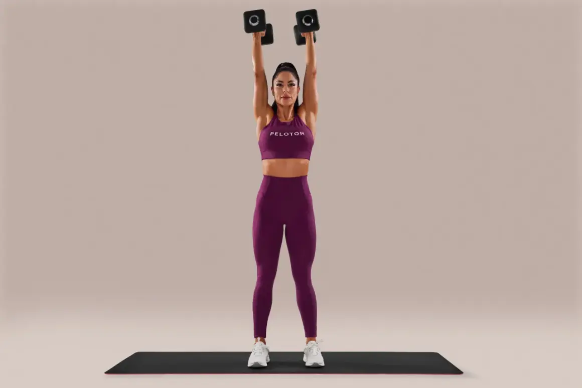 Woman performing arm-toning exercises for females with weights, holding dumbbells overhead.