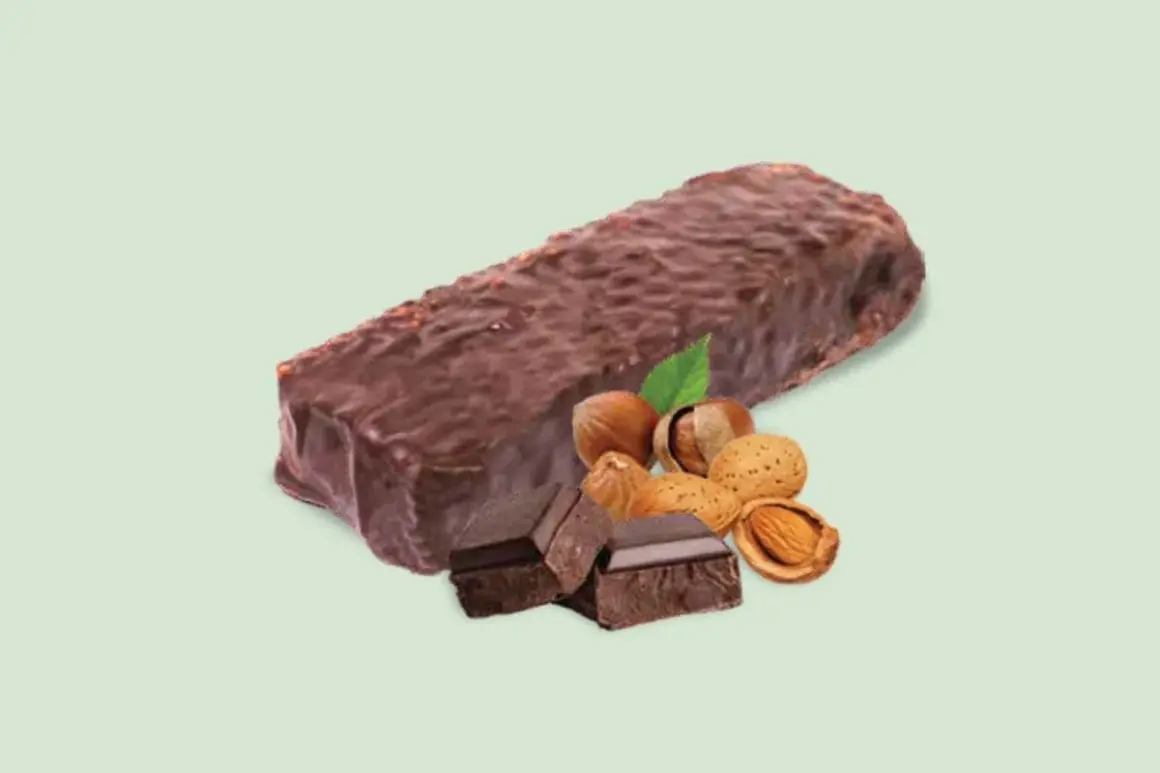 Barretta proteica dopo allenamento, ricoperta di cioccolato, con nocciole, mandorle e pezzi di cioccolato fondente.