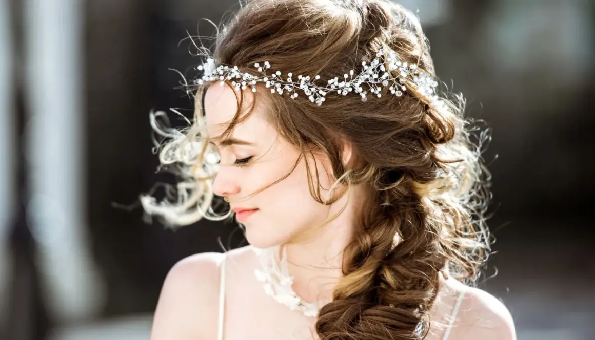 Une jeune femme avec une coiffure bohème, ornée d'une tiare scintillante, ses cheveux ondulés tombant en tresse.
