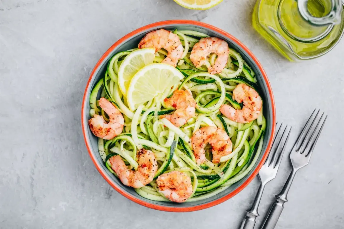Piatto di spaghetti di zucchine con gamberetti saltati e spicchi di limone. Un modo semplice per imparare come cuocere i gamberetti surgelati.