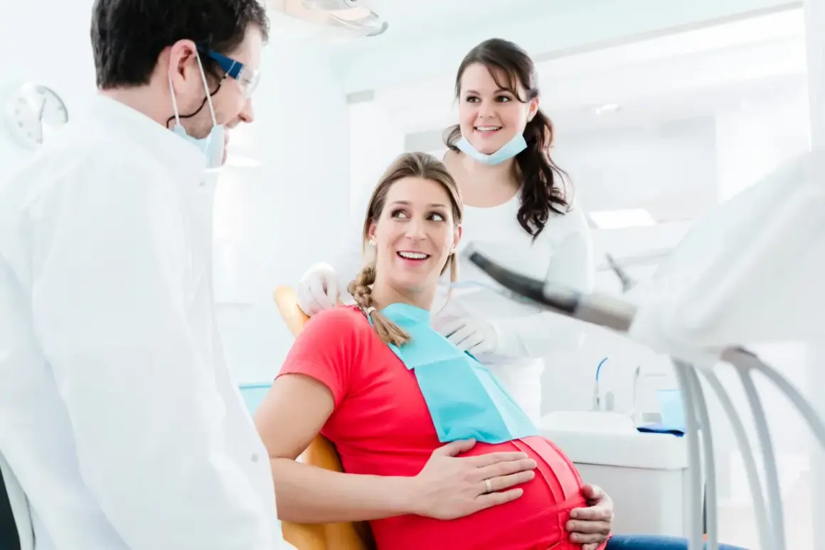 Uśmiechnięta ciężarna pacjentka u dentysty. Dbałość o zęby w ciąży to podstawa.