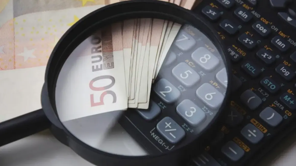 Lupe über 50-Euro-Scheinen und einem Taschenrechner. So wird die Frage "wie viel verdient man im Referendariat" visuell beleuchtet.