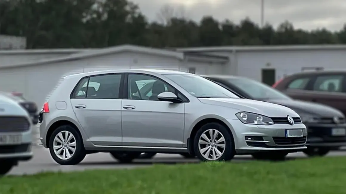 Silver tsi golf parkerad på en gräsmatta framför en vit byggnad.
