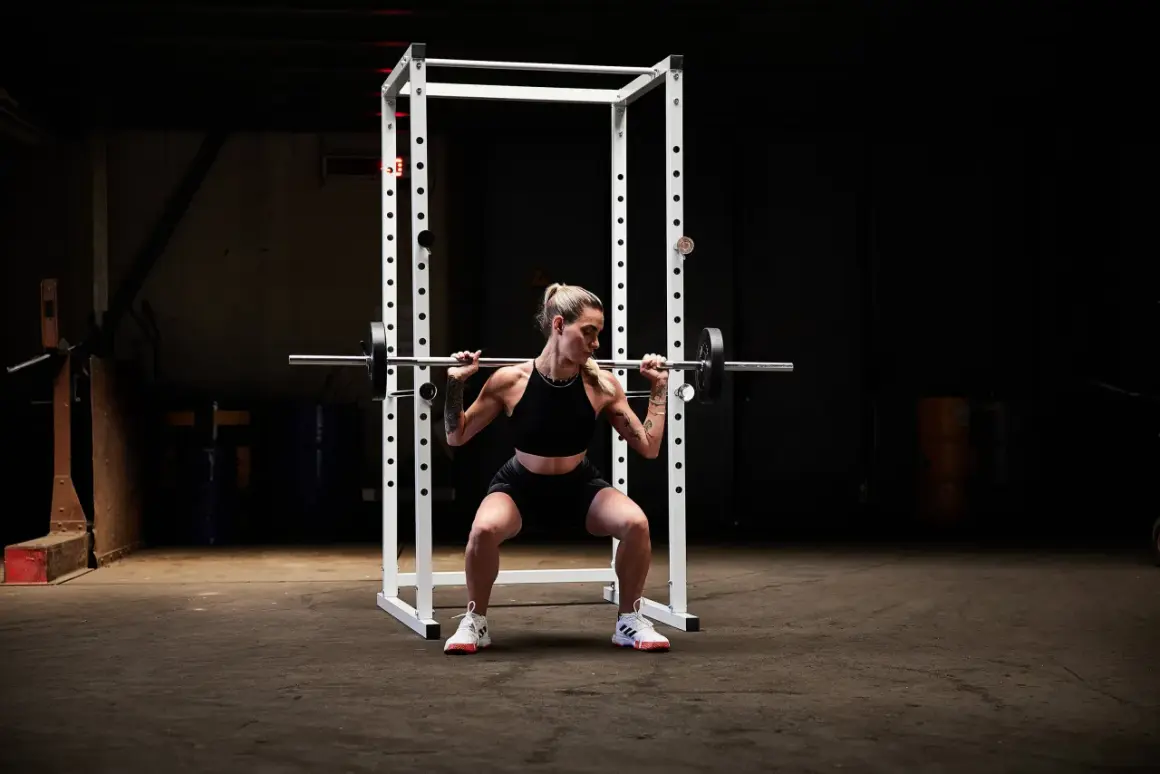 Kvinna utför squats med stång i ett gym.