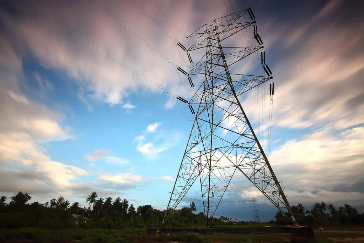 Wieża energetyczna na tle nieba z chmurami. Linie energetyczne, jak taryfa G13, łączą krajobraz.