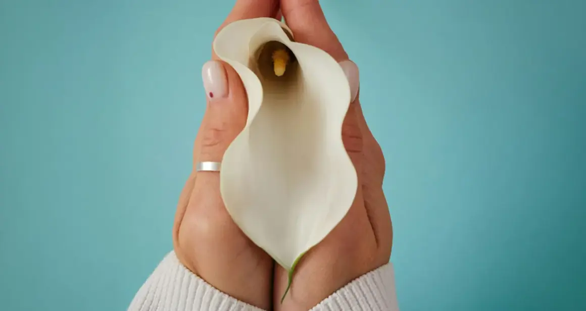 Mains tenant une calla blanche, évoquant la délicatesse et la guérison après une douleur périnée après accouchement.