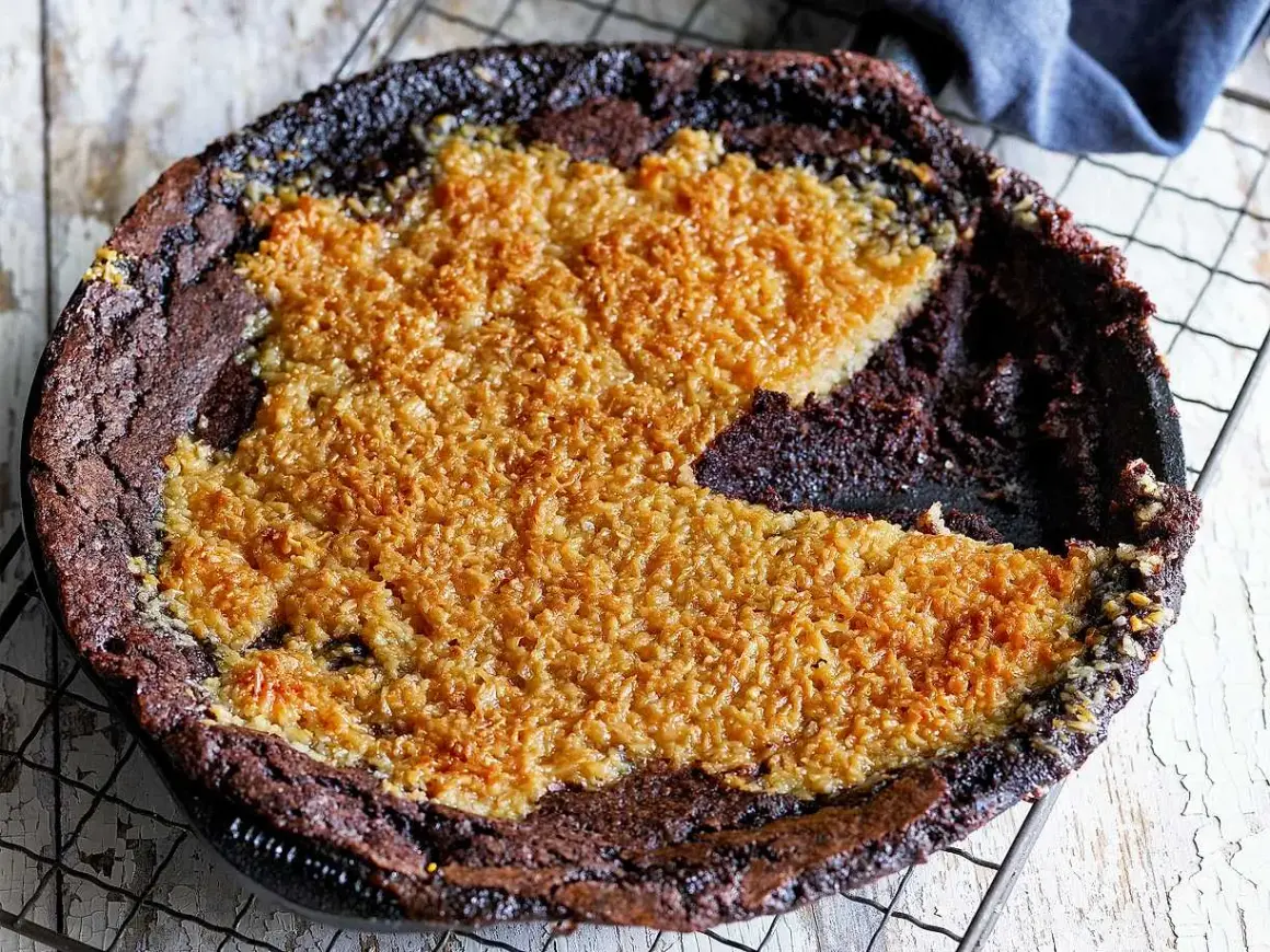 En kladdkaka med kokostosca, med en härlig seg chokladbotten och ett gyllene, krispigt kokostäcke.