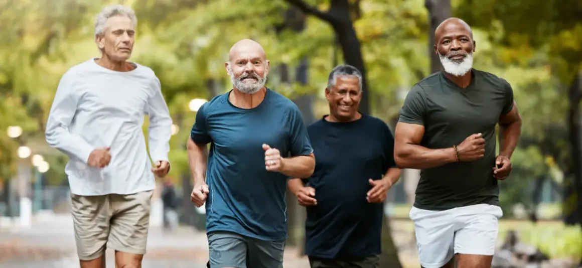 Quatre hommes d'âge mûr profitent d'une course matinale dans un parc, démontrant une excellente motricité adulte.