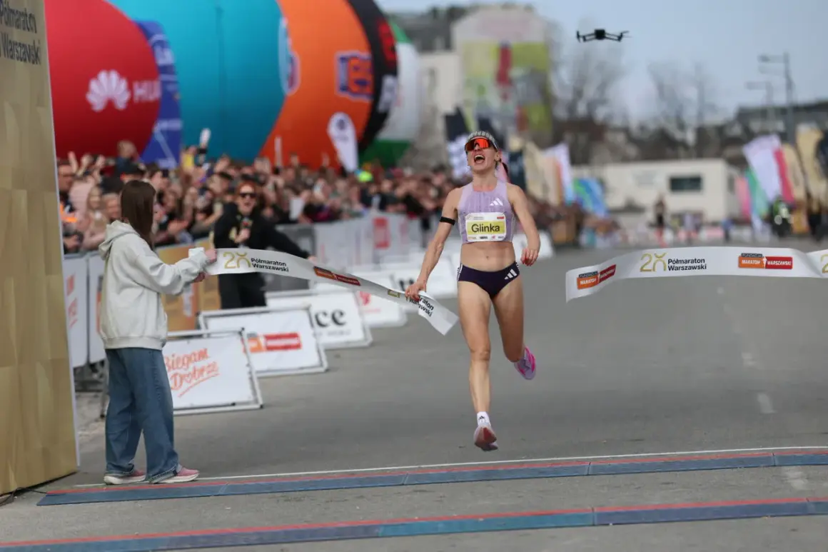 Radość na mecie Półmaratonu Warszawskiego 2026. Zawodniczka Glinka przekracza linię mety, a tłum wiwatuje.